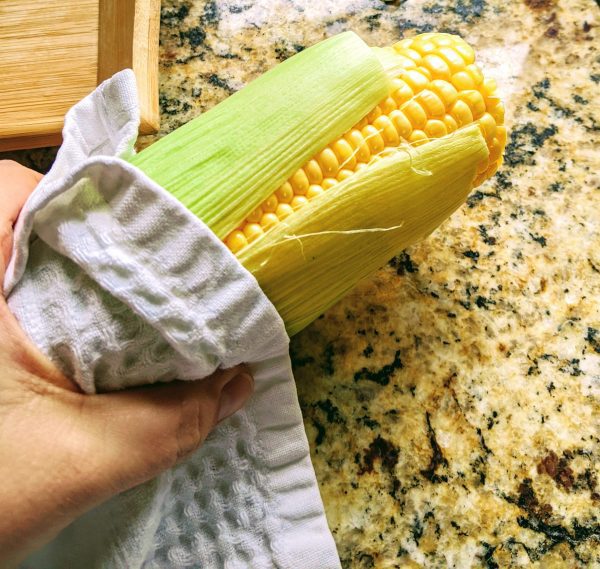 microwave corn on the cob in person's hand