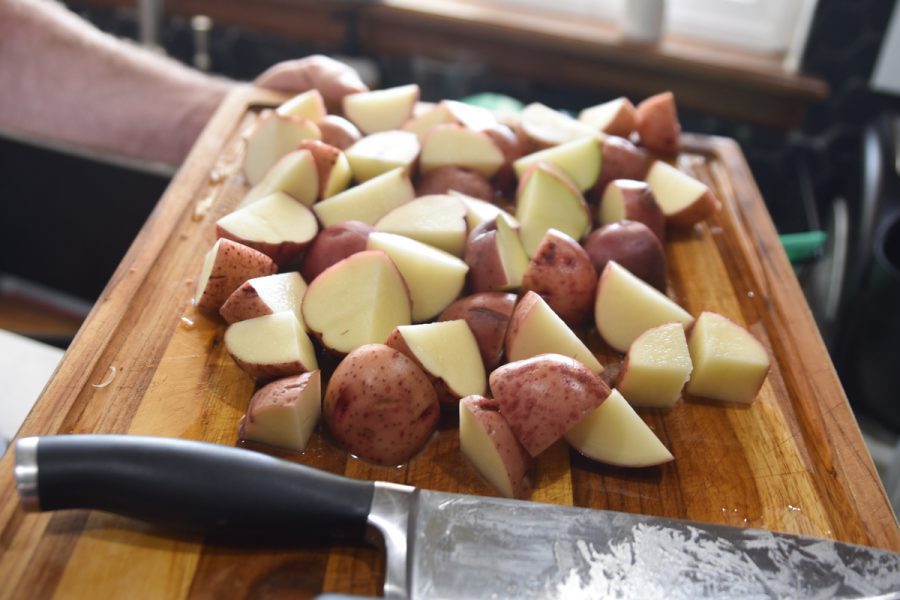 Quartered red potatoes on cutting board.
