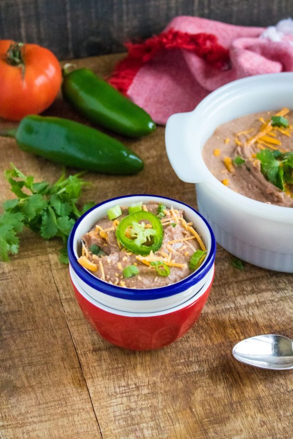refried beans in red bowl with jalapeno on top 