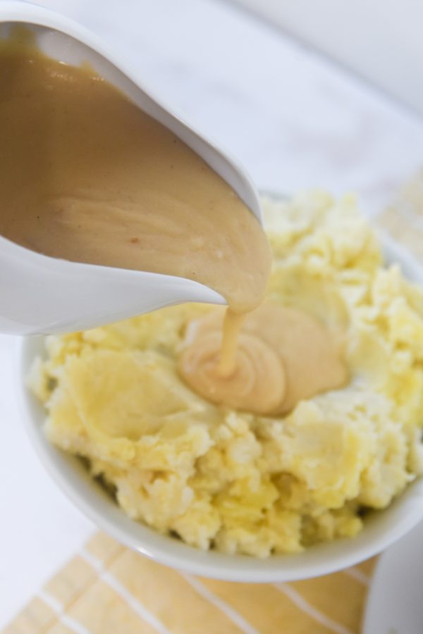 pouring gravy on top of mashed potatoes