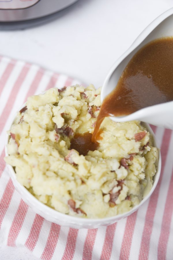 pouring gravy on top of mashed potatoes