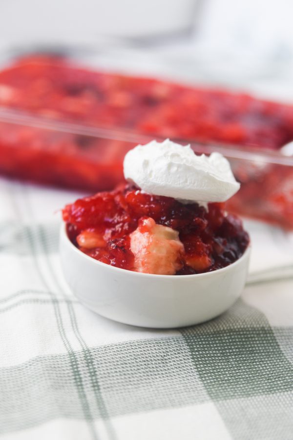 raspberry jello salad in a bowl with whipped cream