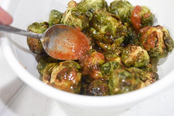 pouring sauce on top of brussel sprouts