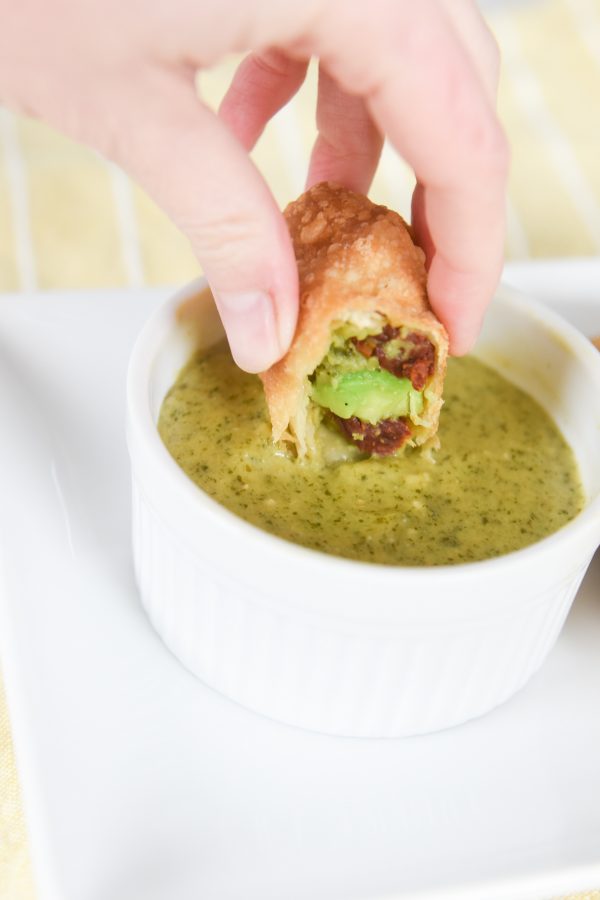 dipping avocado egg roll in sauce