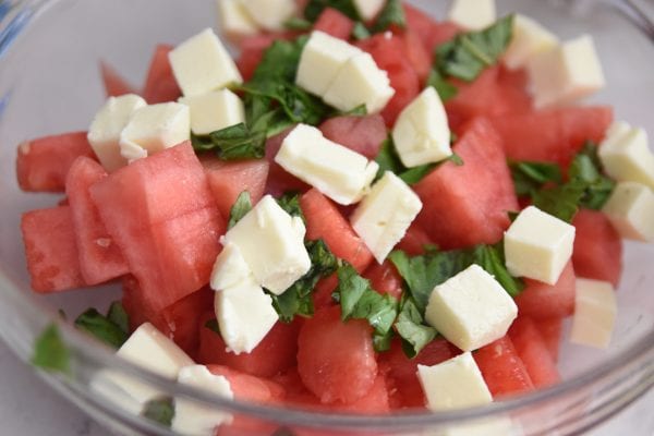 mixing together watermelon salad