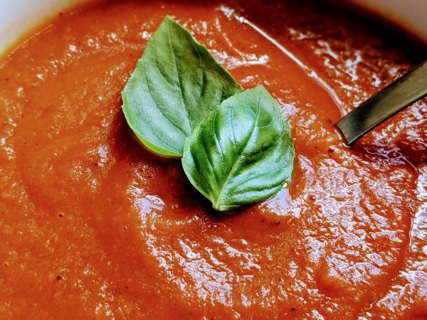 bowl of tomato basil soup with basil leaves on top