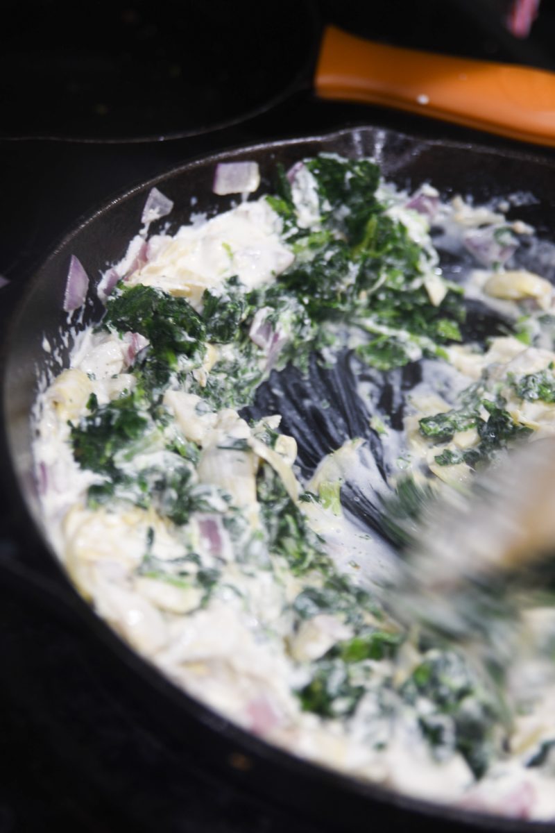 mixing in spinach and artichokes