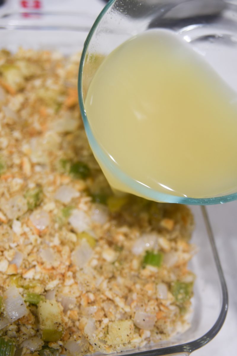 pouring chicken broth over stuffing